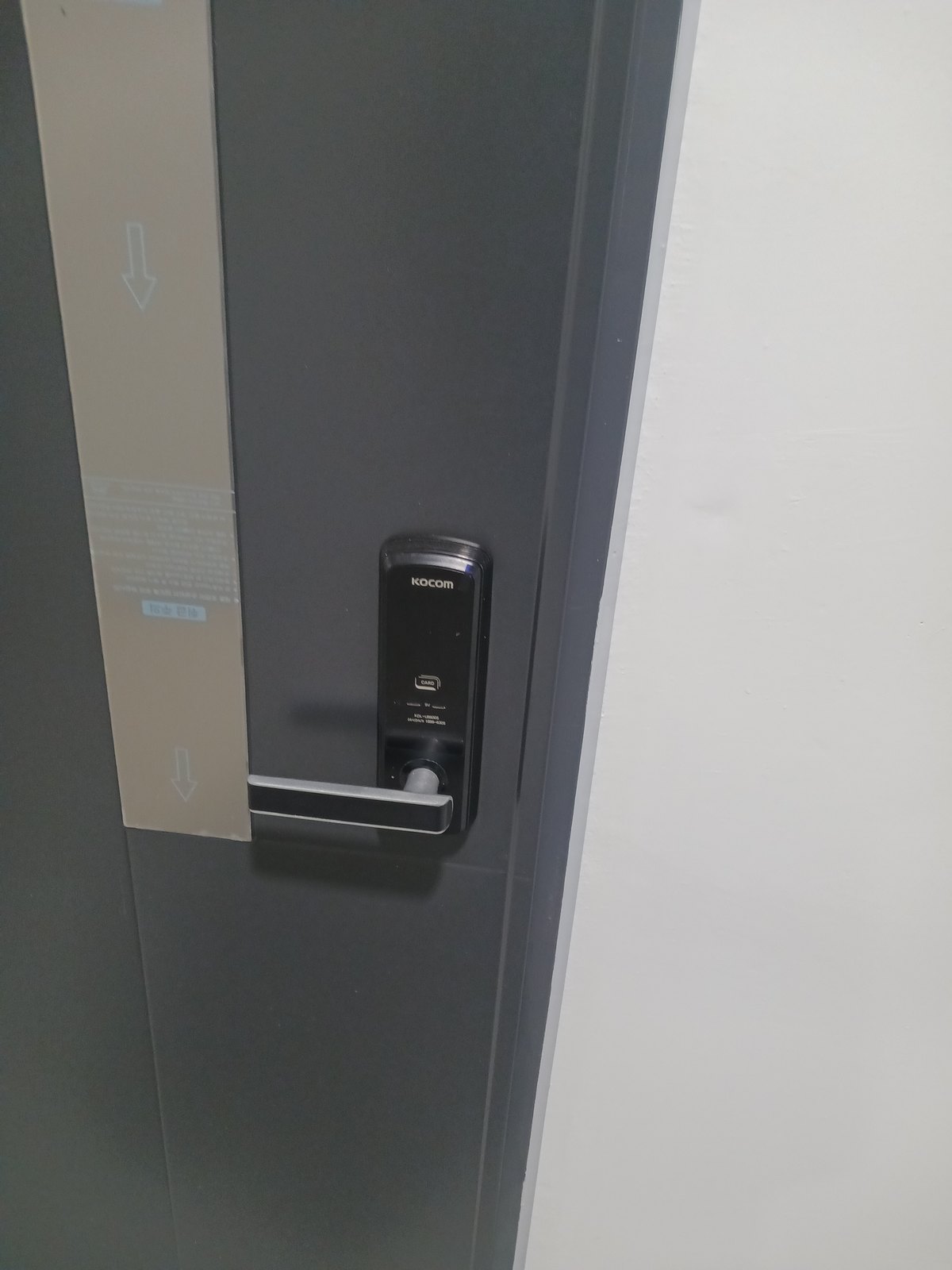 용산구 용문동 출장 — 짙은 회색 문에 단 검은 레버형 도어락과 왼쪽의 안내 필름 띠